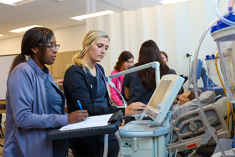 respiratory students checking equipment screen in lab