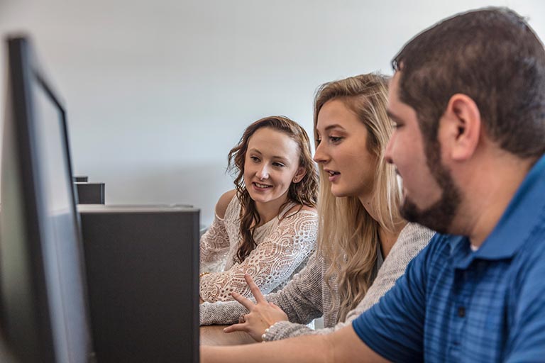 three students working together in a computer lab